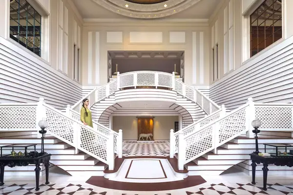 A woman in a dress walks down a white staircase in the Oberoi Amarvilas hotel