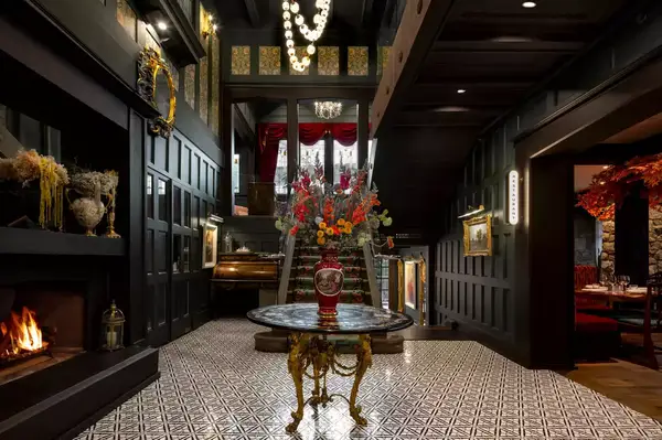 An elegant lobby interior featuring a central table with a flower arrangement, a staircase, and decorative elements