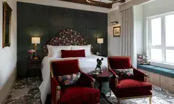 Elegant bedroom with a large bed, decorative chairs, bedside lamps, and a window seat