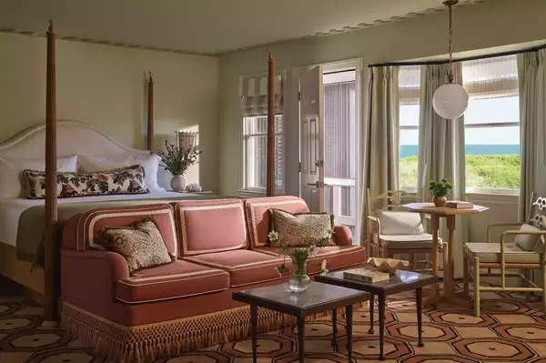 A well-furnished hotel guest room with a bed, sofa, ocean view, and natural light