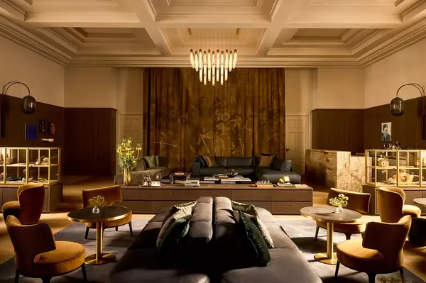 A luxurious library room with modern furniture and decorative lighting, featuring bookshelves, a seating area, and standing lamps