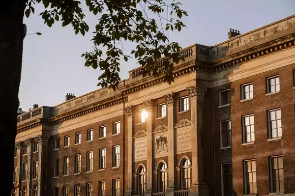 Exterior of the Rosewood Amsterdam building with classic European architecture, framed by tree foliage in the foreground