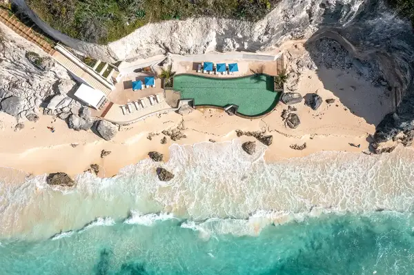 View of a beachside pool with nearby ocean waves and surrounding sandy shore in Bermuda