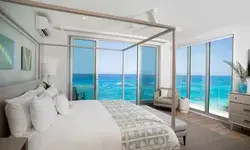Spacious bedroom with a large bed and oceanfront view through glass walls