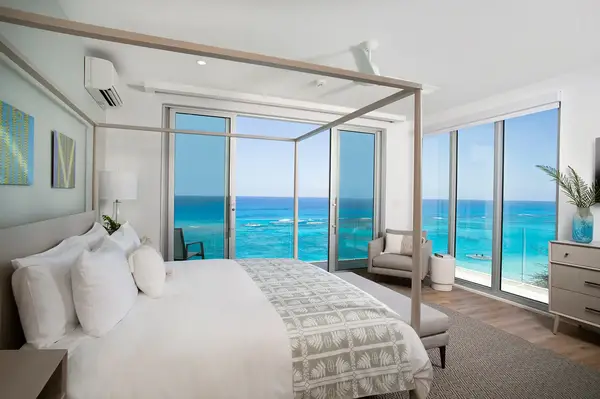 Spacious bedroom with a large bed and oceanfront view through glass walls