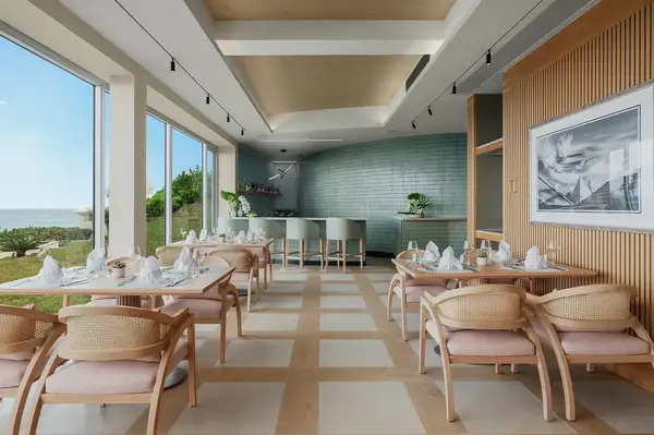 Interior of a modern restaurant with tables, chairs, and large windows overlooking the outdoors