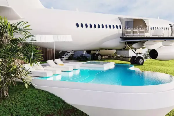 Exterior of Boeing 737 turned luxury villa with pool and lounge chairs. The wing of the plane is a terrace for the villa