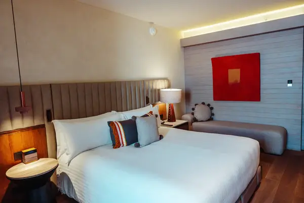 Hotel room with bed, decorative pillows, and a sitting area with minimalist decor