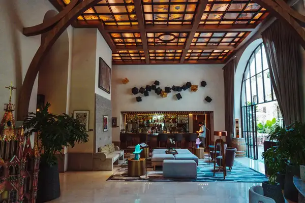 A modern lounge with a bar, comfortable seating, and a high ceiling with decorative lights