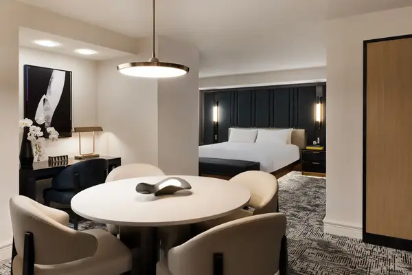 Luxury hotel suite with a seating area and a bed visible in the background