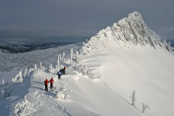 Skiers at the top of a very steep mountain getting ready to ski down