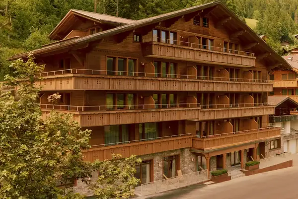 A chalet-style building with balconies surrounded by trees