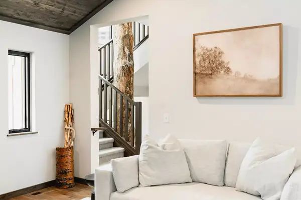 Living room interior with a sofa, stairs, wall art, and a tree trunk accent