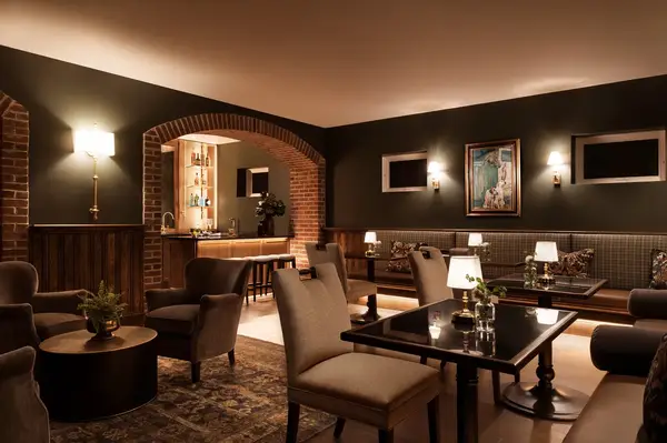 A stylish lounge with tables chairs sofas a bar area and wall lighting