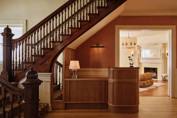 Wooden staircase with a small reception desk beneath, leading to an adjacent furnished room