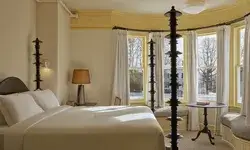 A cozy bedroom with a bed, a table near a window, and bright natural light