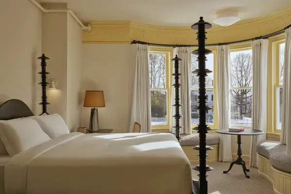 A cozy bedroom with a bed, a table near a window, and bright natural light