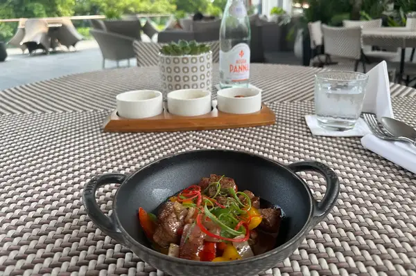 Dining table setting with a dish of cooked food at an outdoor seating area