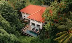 Colonial-style villa with a pool amidst lush greenery