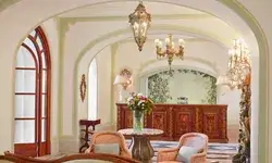 Lobby interior with chairs, a table with flowers, and a reception desk in the background