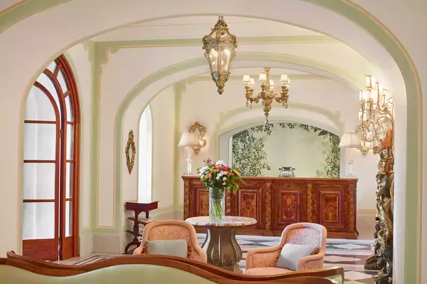 Lobby interior with chairs, a table with flowers, and a reception desk in the background