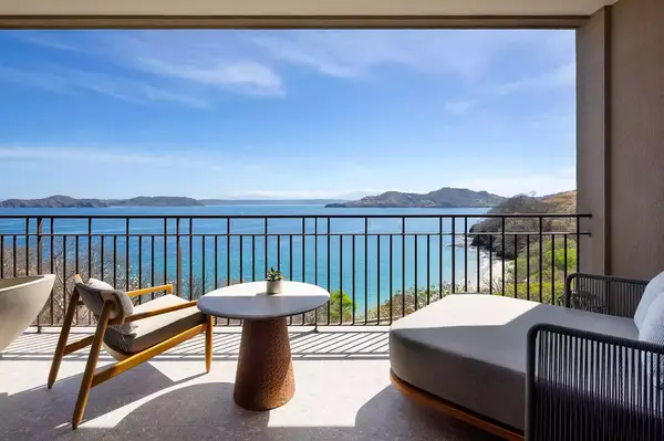 View of a coastal ocean scene from a balcony with chairs and a table