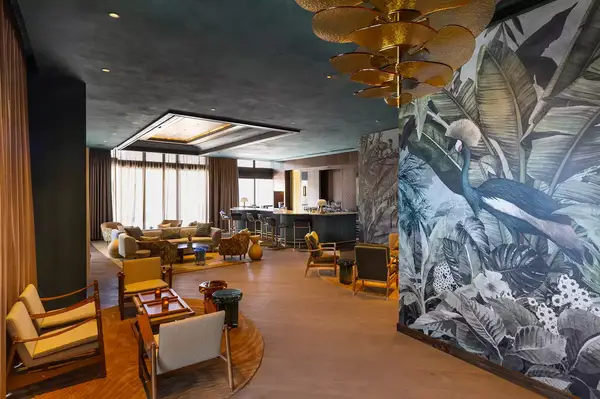 A lounge area with seating, a bar counter in the background, and a mural of a peacock on the wall