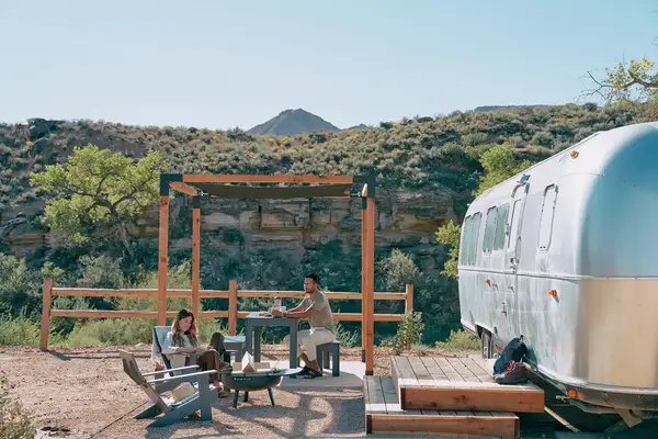 A man and woman sitting outside their air stream at at AutoCamp Zion