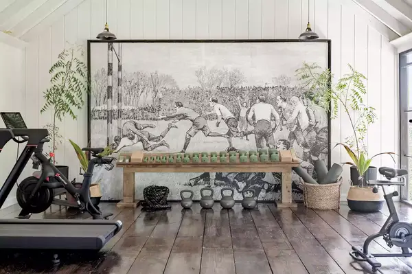 A home fitness space featuring exercise equipment and a rustic aesthetic, with a large mural as the centerpiece