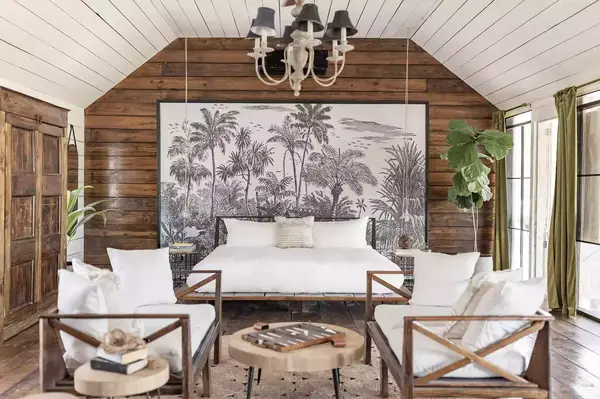 Rustic bedroom with wooden furniture and tropical wall art, located in a farmhouse setting