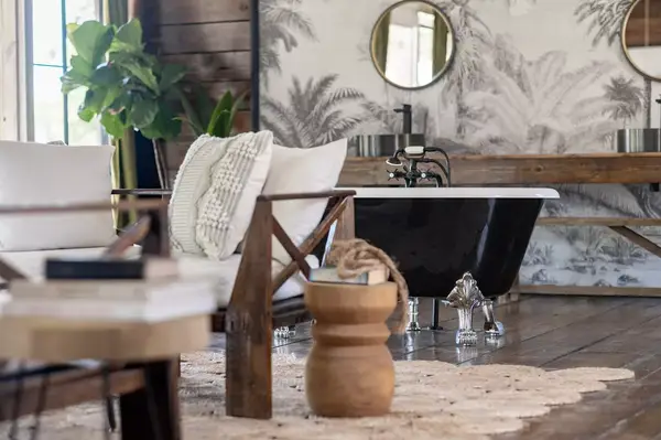 A seating area and a clawfoot tub in a rustic bathroom with natural decor elements and wooden accents