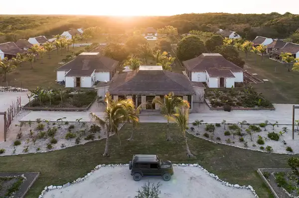 An aerial view of a resort-like property featuring multiple buildings, landscaped gardens, and a vehicle parked in the center driveway