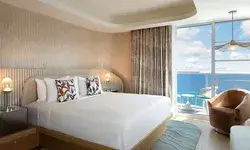 Modern bedroom with a large bed, ocean view balcony in the background