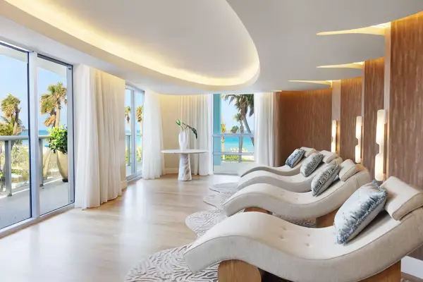 A spa lounge with curving recliners overlooking a tropical outdoor view through large windows