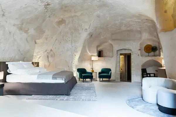 A spacious room with a bed, chairs, and modern decor set within curved stone walls