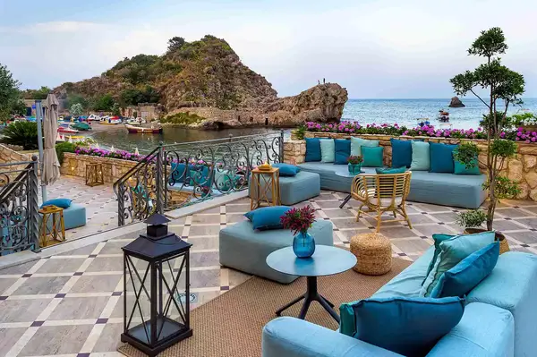 Elegant outdoor lounge area with seating and a sea view, located at a hotel terrace by the water in Italy