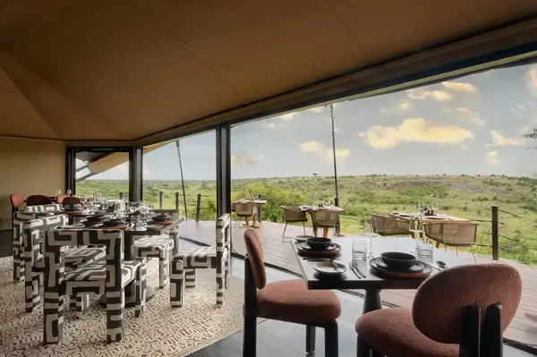 Dining area with tables and chairs overlooking a scenic landscape through open windows