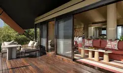 Luxurious tented suite with a deck outdoor seating area and views of indoor furniture in Mahali Mzuri