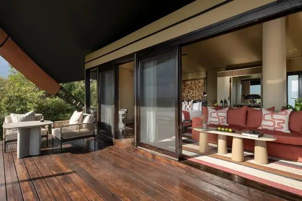 Luxurious tented suite with a deck outdoor seating area and views of indoor furniture in Mahali Mzuri