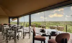Dining area with tables and chairs overlooking a scenic landscape through open windows