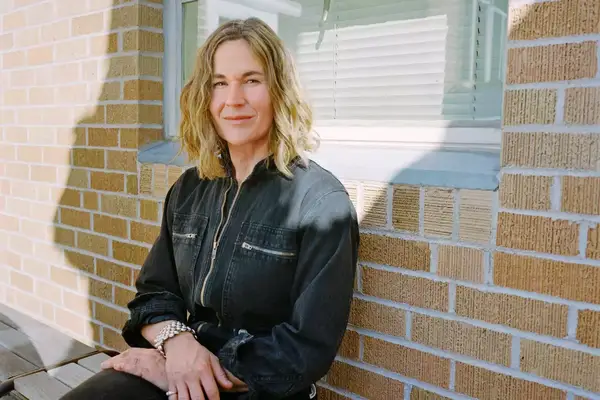 Jen Turner site in front of a brick wall at The Carpenter Hotel