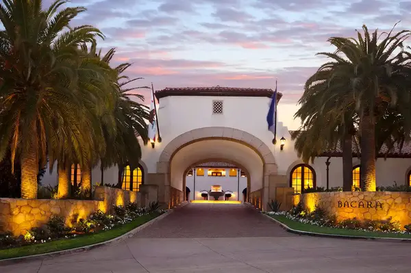Entrance view of The Ritz-Carlton Bacara in Santa Barbara, flanked by palm trees and softly illuminated at sunset