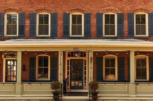 Exterior of a hotel with decorative blue shutters and a central entrance, 435 displayed above the door