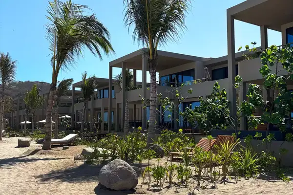 Exterior view of luxury resort buildings with palm trees and beach surroundings, modern architecture and tropical environment