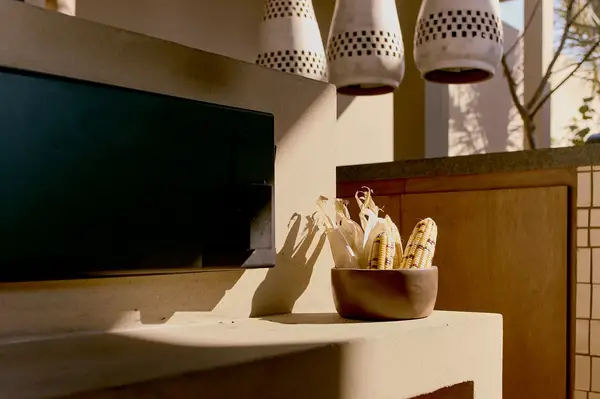 A bowl containing vegetable items on a counter, geometric lighting fixtures hanging overhead