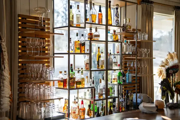 Display shelf with bottles and glassware, background window view