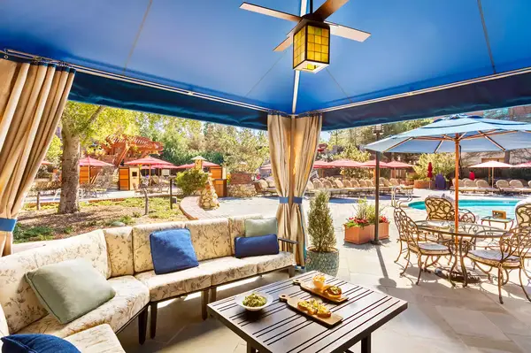 Poolside cabana with seating and a view of the pool and surrounding area, featuring a dining table and refreshments on a central table