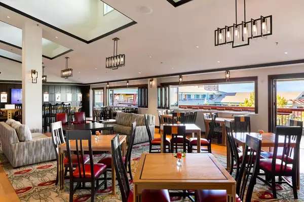 A dining area with tables, chairs, sofas, and large windows overlooking a rooftop