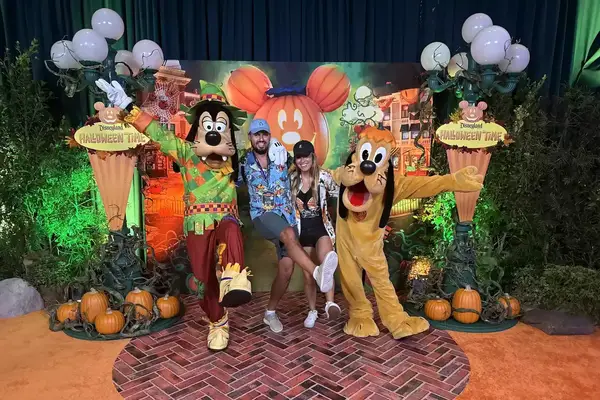 T+L editor Nina Ruggiero and her husband Alex pose at Disneyland with Goofy and Pluto