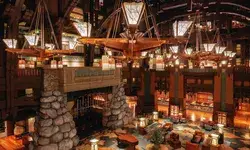 View of the Grand Californian Hotel lobby at Disneyland, featuring rock pillars, wooden chandeliers, and seating areas.
